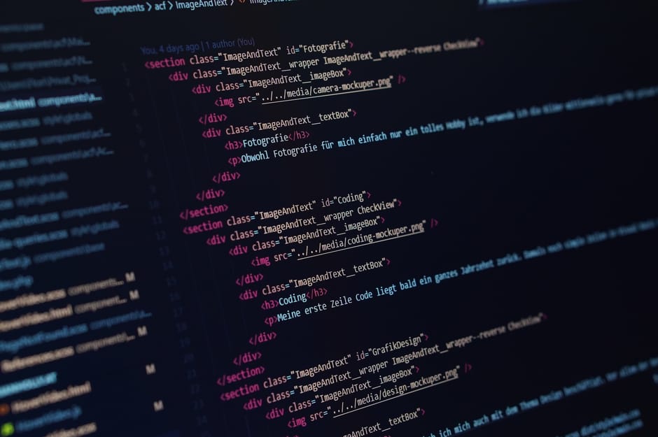 A close-up photograph of a computer screen displaying lines of HTML and CSS code, with visible elements such as meta tags, title, links to stylesheet and favicon. The code is highlighted with differen